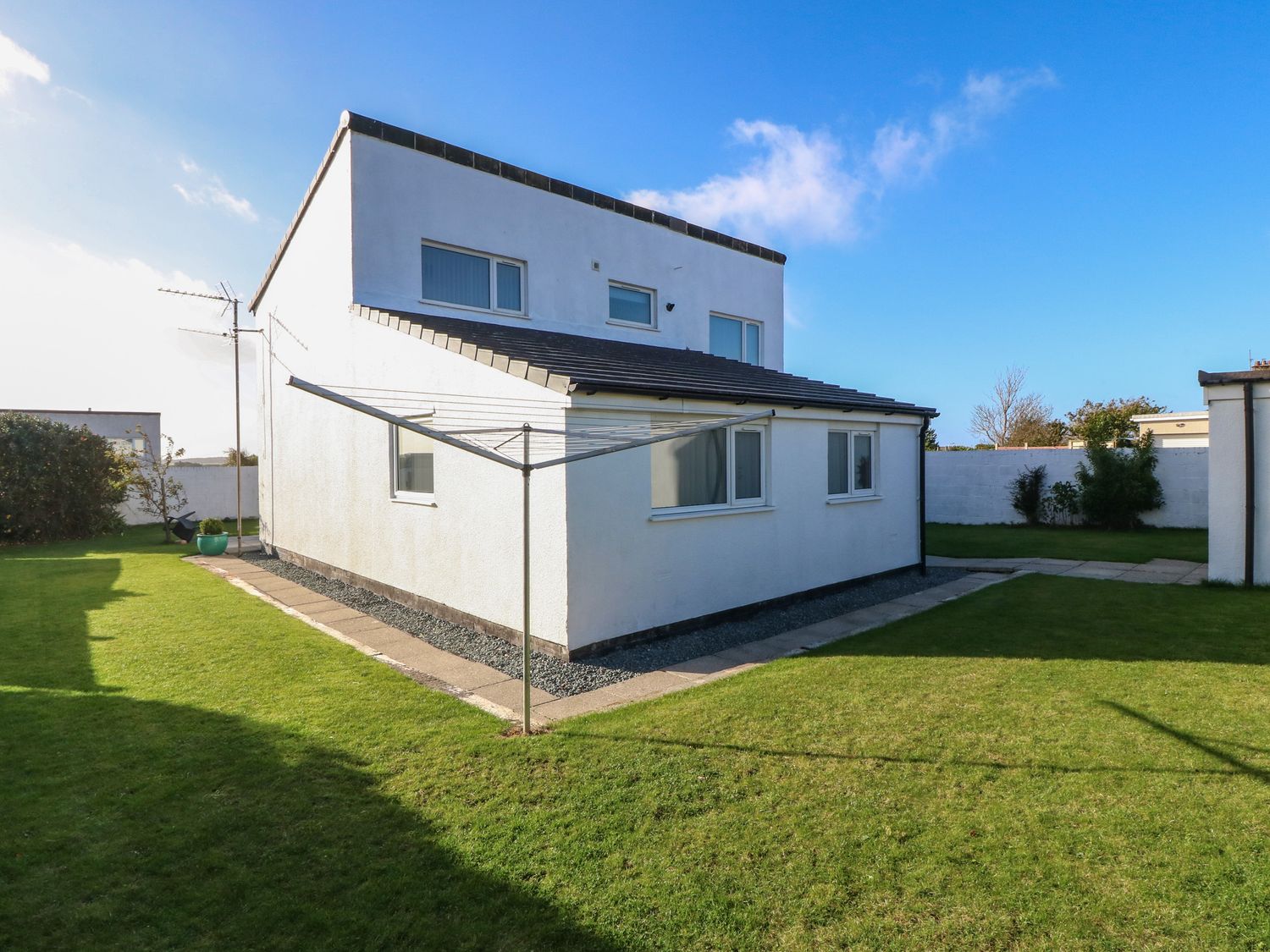 A white two-story house with grass lawn and a rotary clothesline at Beach Reach in Valley