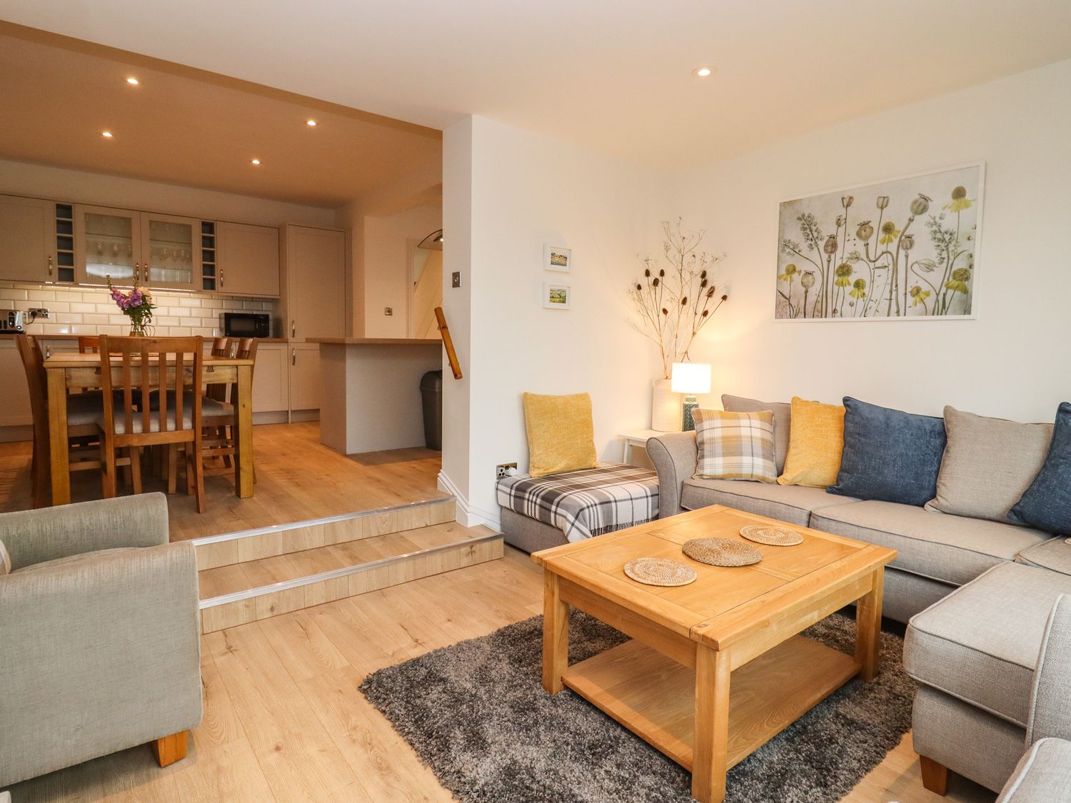 A living room with a wooden coffee table and sectional sofa next to a dining area with a wooden table and chairs at Delabere Road in Bishops Cleeve