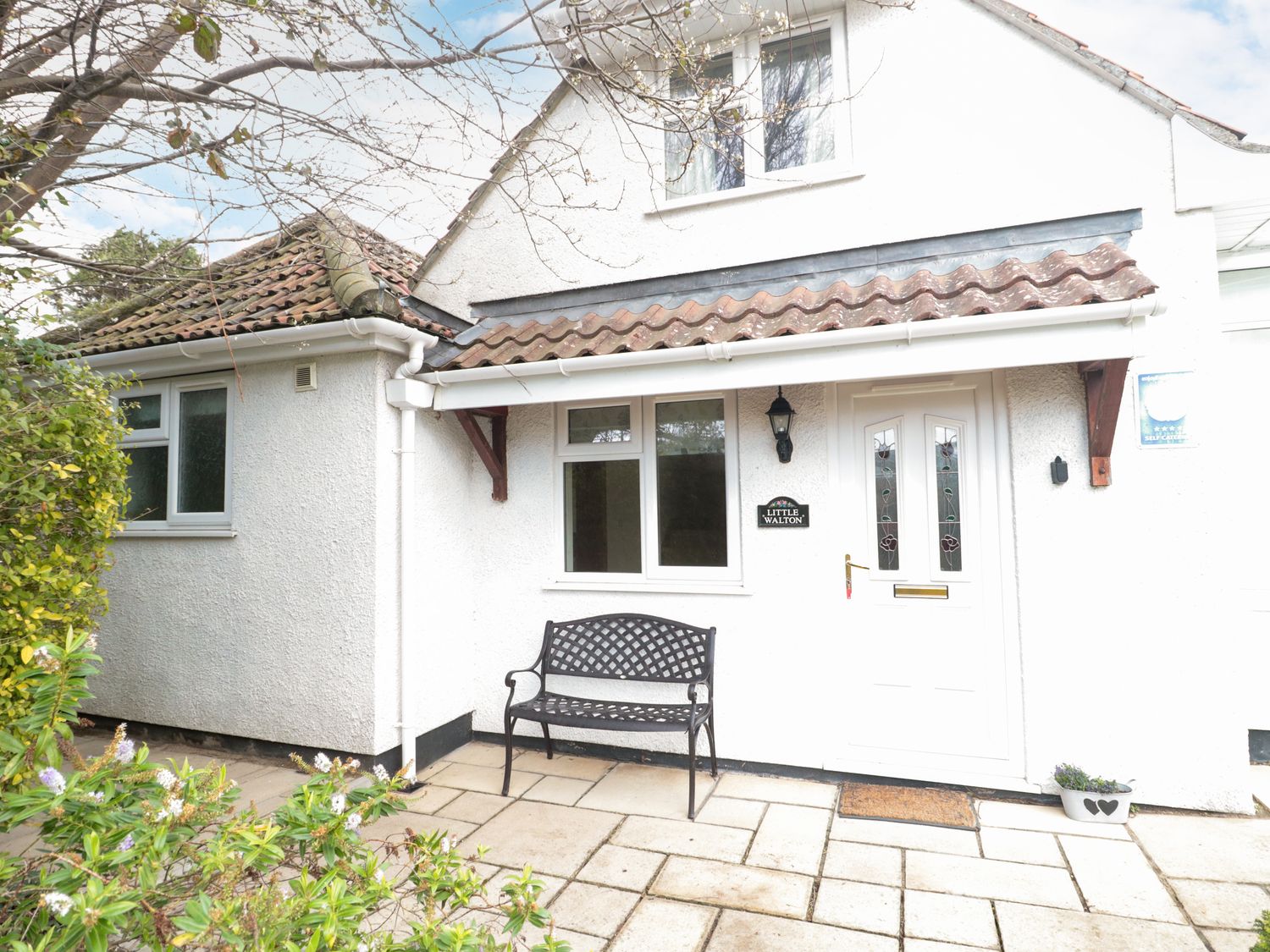 A front porch with a bench a white door and a window at Little Walton in Burnham-On-Sea
