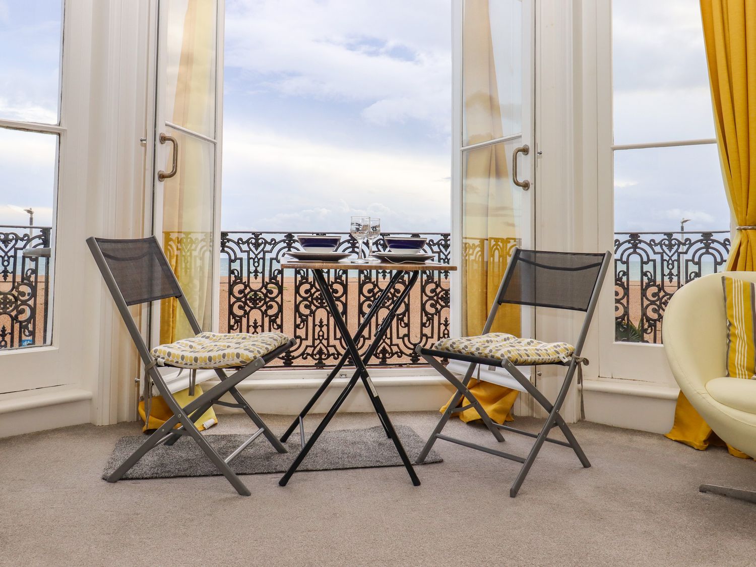 A small dining table with two chairs and a balcony with ornate iron railing at The Old Spy Headquarters in Folkestone