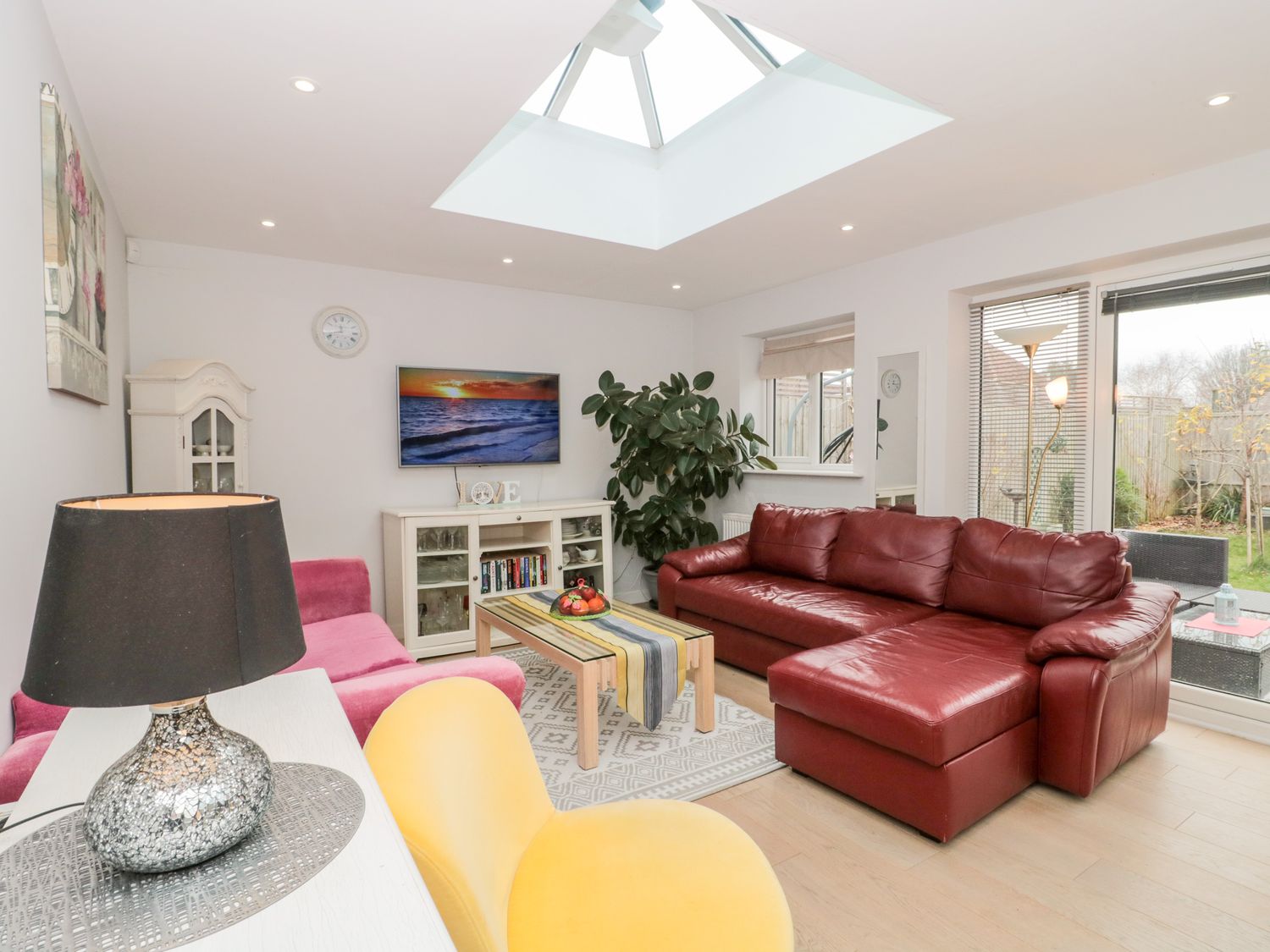 A living room with red leather sofa yellow chair coffee table and TV at Paradise Villa in Highcliffe