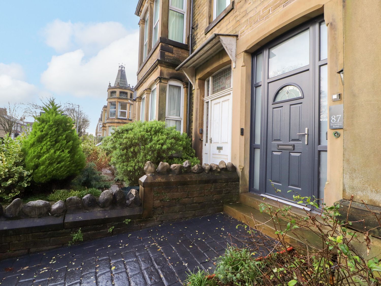A stone pathway leading to two front doors with stone walls and shrubs along a street at Inglemead in Morecambe