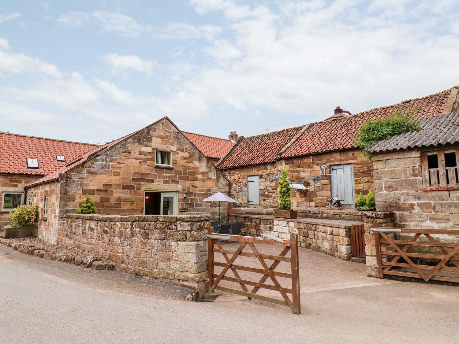 A courtyard with stone buildings and wooden gates at Mulgrave Cottage Dalehouse near Staithes