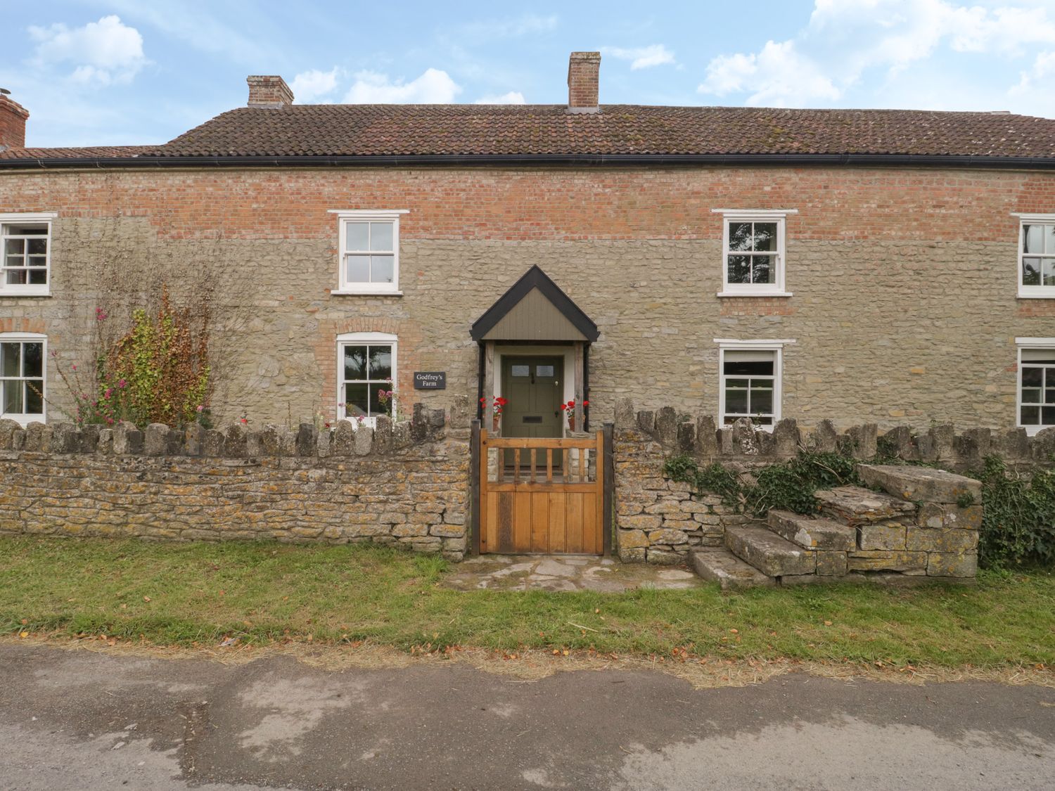 A stone and brick house with a small wooden gate and stone wall in front at Drover's in Sutton Mallet