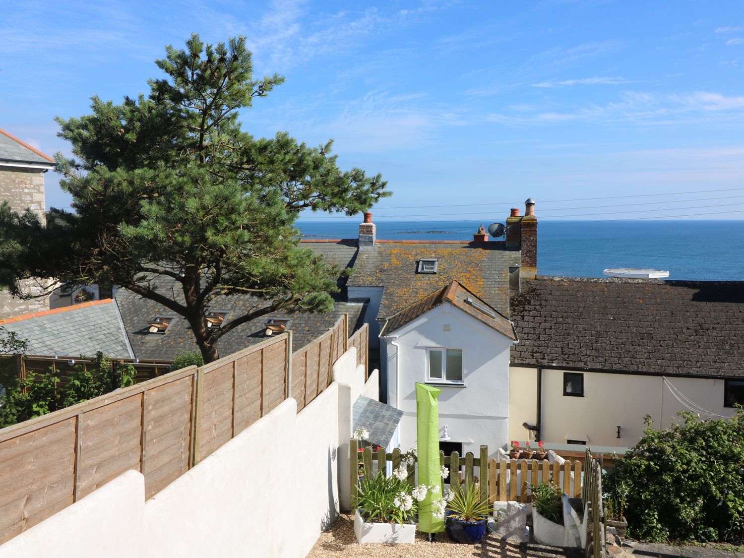 A coastal view with houses a tree and a fenced garden at Ner Sea in Marazion