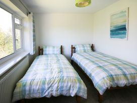 A bedroom with two single beds and plaid bedding a window with curtains and a painting on the wall at Anglesey White Haven in Llandegfan near Menai Bridge