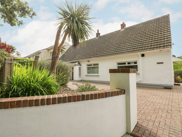 A white house with a tiled roof and paved driveway with plants and a small wall at Ashdown House in Saundersfoot