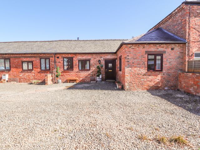 A brick house with multiple windows a dark door and a gravel driveway at Clwyd Cottage in St Asaph