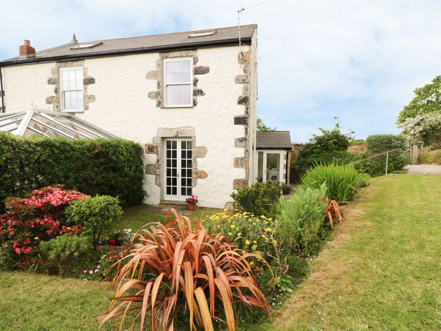 An exterior view of a white stone house with a garden and a variety of plants at Old Chapel Cottage Trescowe near Praa Sands