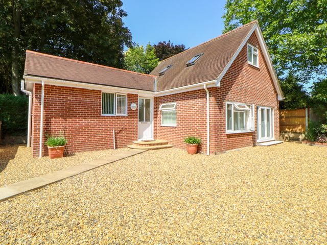 A brick house with a tiled roof and multiple windows surrounded by gravel and plants at The Lodge at Orchard House in Norwich