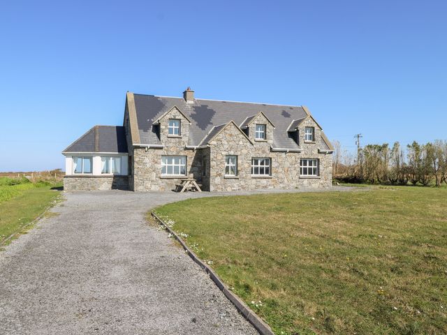 A stone house with multiple windows and a gravel driveway surrounded by grass at Realt na Maidne in Claddaghduff County Galway