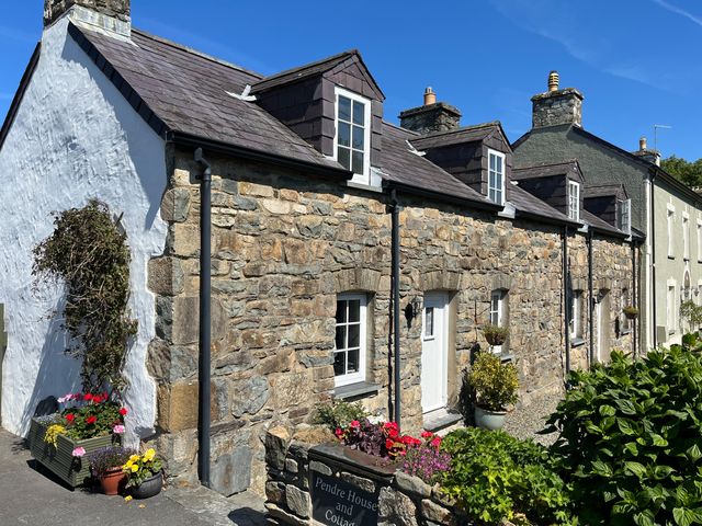 Stone cottages with white windows and doors with flowers and plants outside at End Cottage in Newport Pembrokeshire