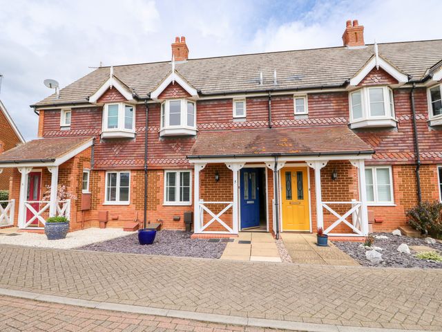 A row of brick townhouses with blue and yellow front doors and small covered porches at 5 Styleman Road in Hunstanton