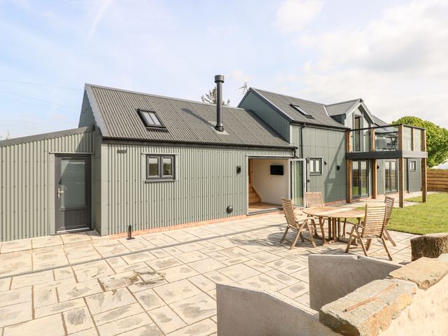 Modern two story house with patio furniture on stone paved area and grass lawn at Glowty Brynbedw in Efailwen