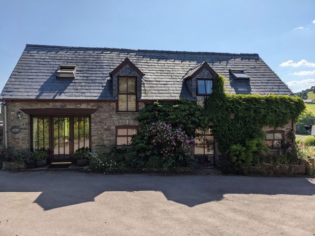 Stone house with slate roof and climbing plants around windows at Caecrwn Battle near Brecon