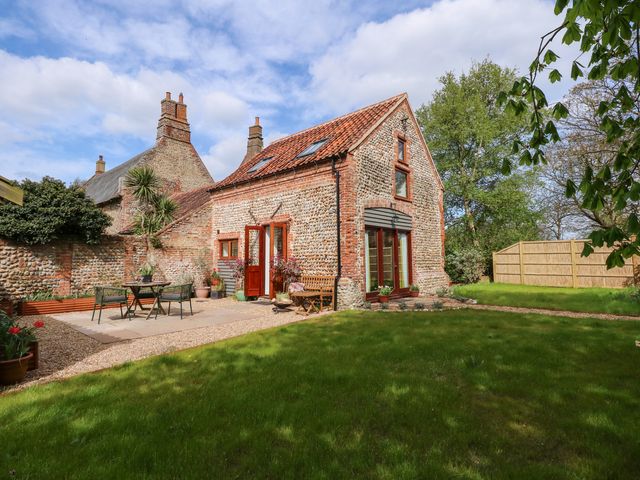 A stone and brick cottage with a tiled roof and a garden with outdoor furniture at The Little Hay Barn in Bacton