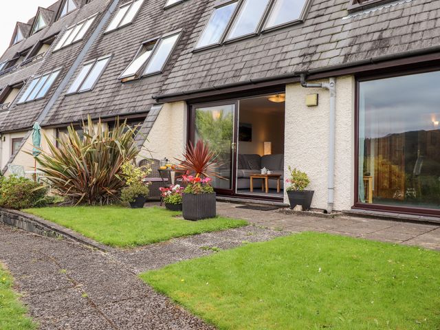 The exterior of a building with large windows and patio doors opening to a garden with plants and a paved path at Pavey Ark in Ambleside