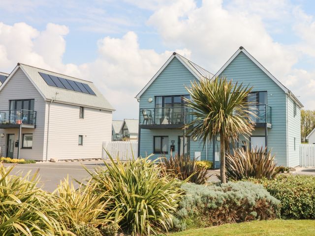 Two modern houses with balconies and solar panels surrounded by plants and a lawn at Seaquel in Westward Ho