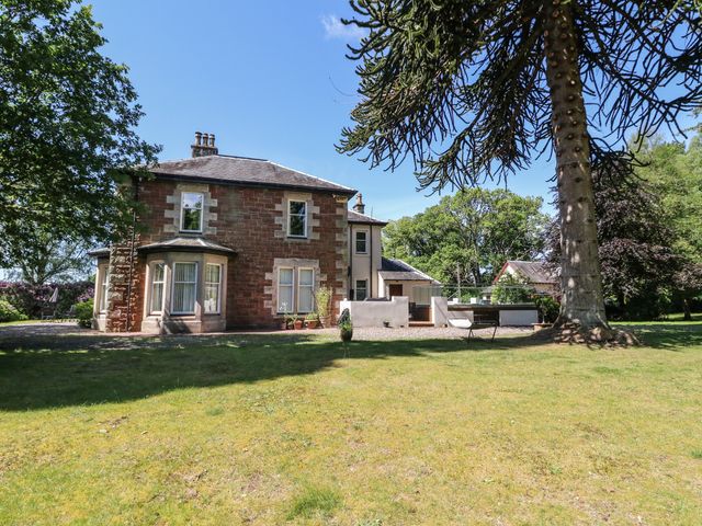 A two-story house with brick and stone exterior surrounded by trees and lawn at Masada in Spean Bridge