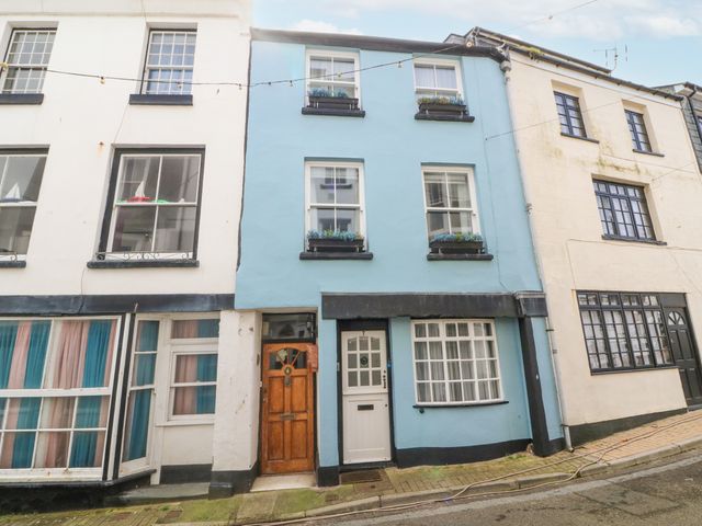 A row of terraced houses with blue and white facades and flower boxes on upper windows at Harbour Cottage in Ilfracombe