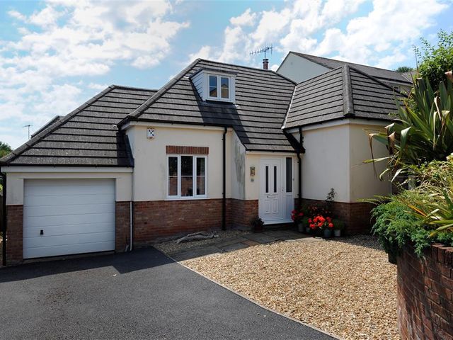 A house with a garage driveway gravel area and plants at 2a St Georges Hill Lyme Regis