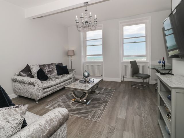 A living room with two silver sofas a glass coffee table and two large windows at Royal Terrace View in Weymouth