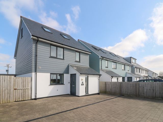 A row of modern two storey houses with grey and white exteriors and paved driveways at Atlantic Reach in Marazion