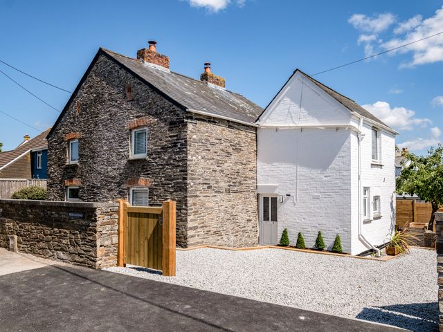 A stone and white brick cottage with a wooden gate and gravel driveway at West Cottage in Rock