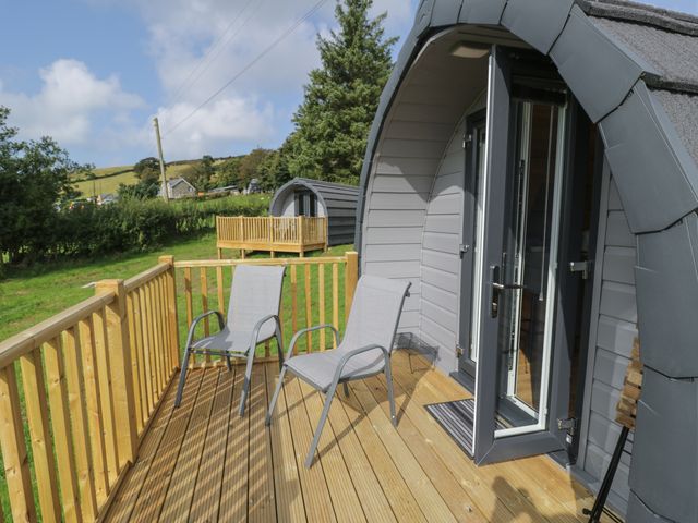 A wooden deck with two chairs outside an arched pod structure at Dysynni Pod in Llanegryn near Tywyn
