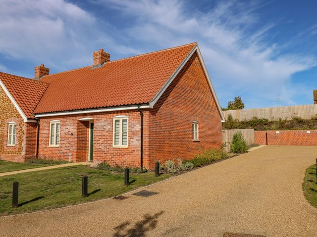 A brick house with a tiled roof and paved driveway at Woodpecker in Hunstanton