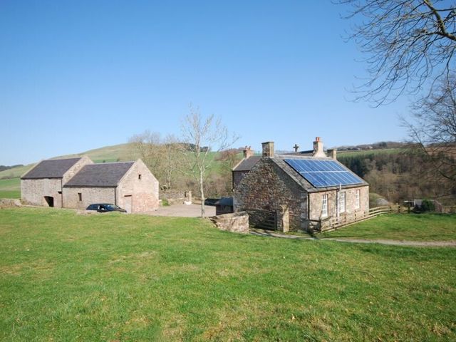 A rural scene with stone buildings and solar panels on one in Kirknowe Jedburgh