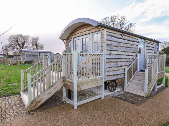 Two wooden shepherd huts with stairs and railings on grassy land at The Fenton in Bolton Percy near Tadcaster
