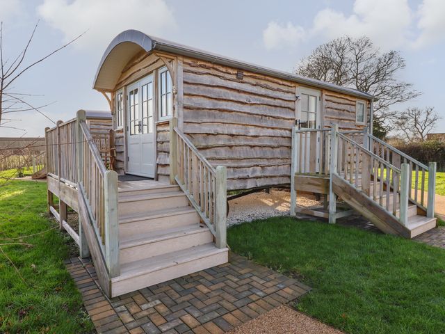 A wooden cabin with two sets of stairs leading to doors surrounded by grass at The Egyptologist in Bolton Percy near Tadcaster