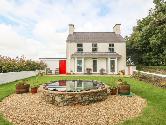 A two story house with a stone pond and garden in front at Bryn Tirion in Llangefni