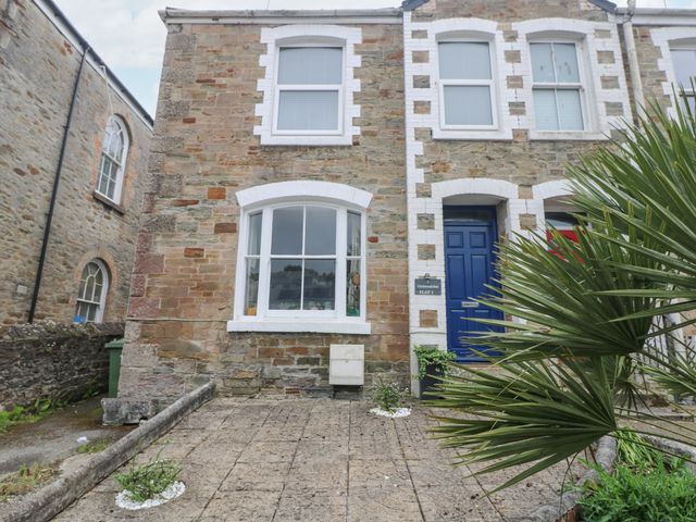 Exterior of a stone building with a blue door and large windows with white frames at The Oystercatcher in Falmouth