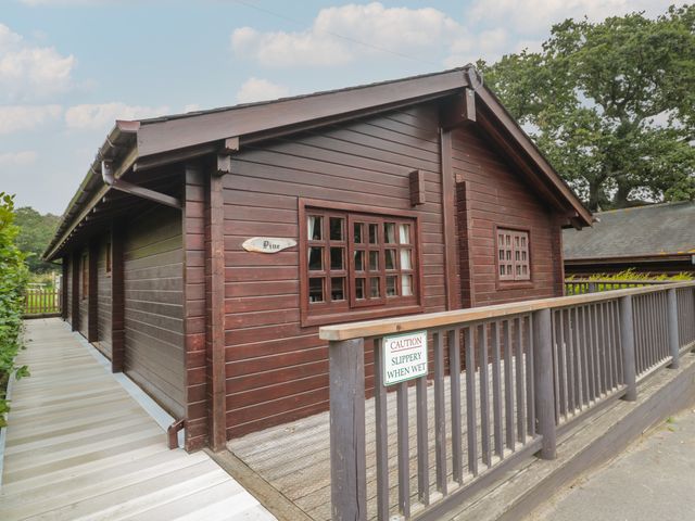 A wooden cabin named Pine with a wheelchair accessible ramp and caution sign at Pine in Swanage
