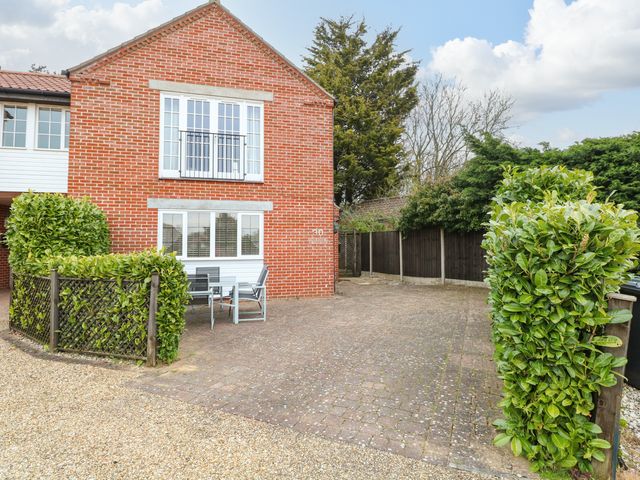 A brick house with white windows and outdoor seating on a paved driveway at 30 Burtons Mill in Stalham