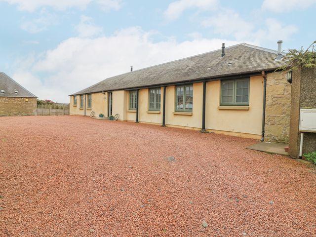 The exterior of a single story building with multiple windows and a gravel driveway at Cartshed in Ednam near Kelso
