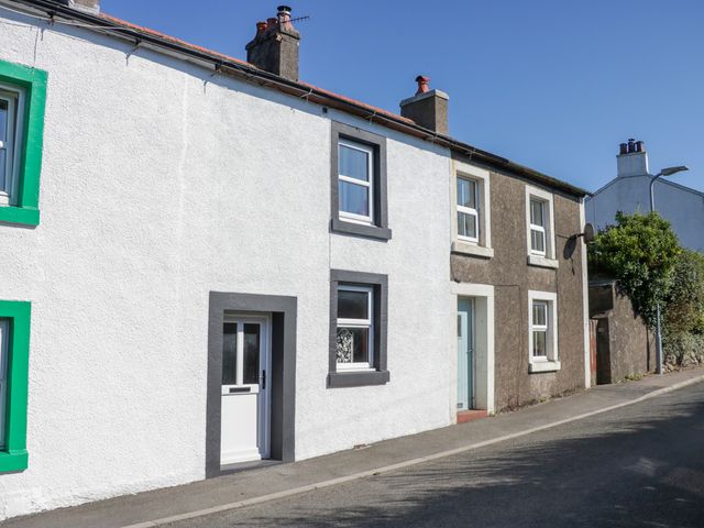 A residential street with terraced houses featuring white and brown exterior walls and framed windows at Whitecroft Nook in Gosforth