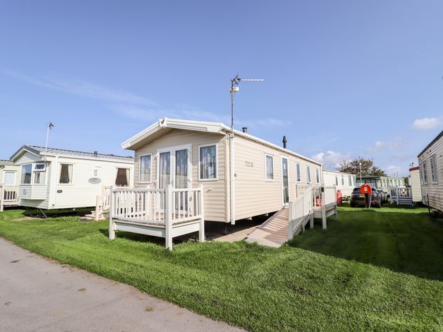 A row of mobile homes with small decks and ramps on grassy land at B15 Ty Gwyn in Towyn