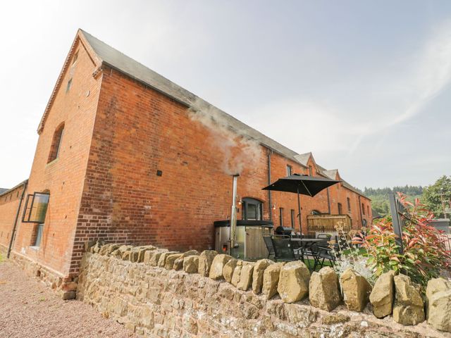 A brick building with outdoor seating area a black umbrella and a stone wall at Plough Share in Huntley