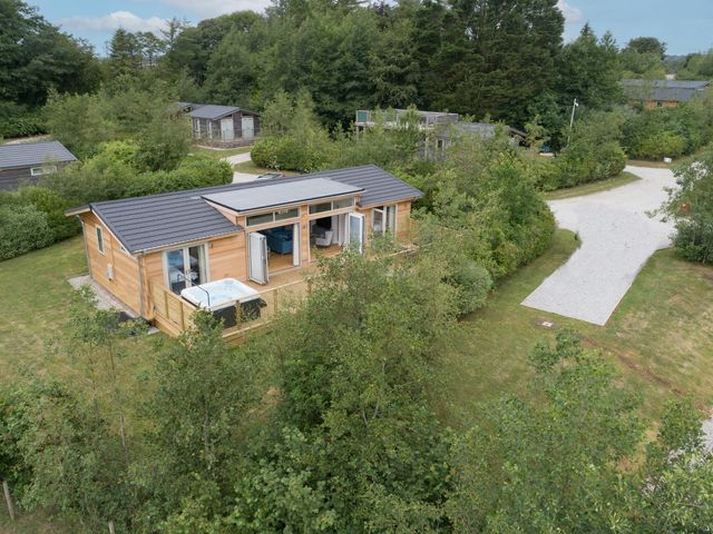 A wooden house with opened doors and a hot tub on the deck surrounded by trees at 5 Southern Place in Dobwalls