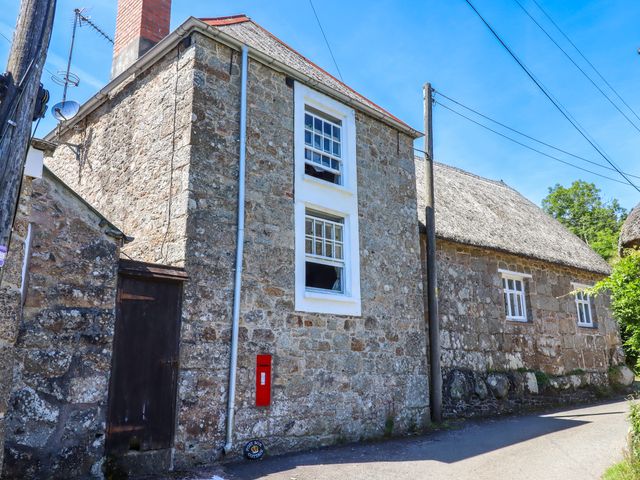 A stone cottage with two windows and a red post box on the wall at Post Box Cottage near Chagford