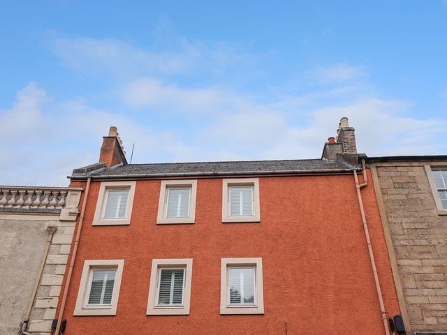 A red building with six white framed windows and chimneys against a blue sky at 26 Woodmarket in Kelso