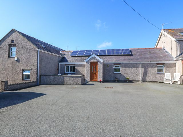 A single story house with solar panels on the roof and a paved driveway at Gwynlys in Cemaes Bay
