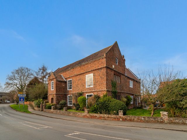 A brick house with windows and bushes along the side of a road at 1 The Grange in Cawood near Ricall
