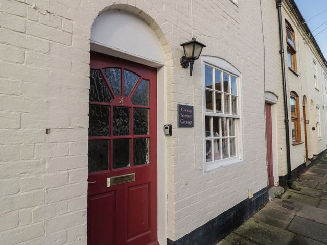 A row of white brick cottages with red doors and windows including Cherry Blossom Cottage in Stratford-Upon-Avon