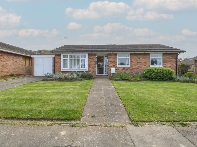 A brick bungalow with a tiled roof a front garden with a path and flower beds at White Lion Retreat in Cromer