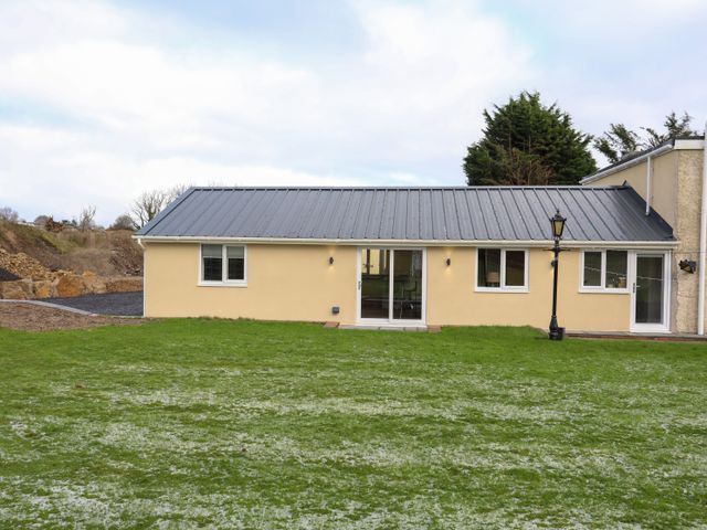 A single story building with a metal roof and several windows on a grassy lawn with a lamp post near Ynys Uchaf Near Benllech