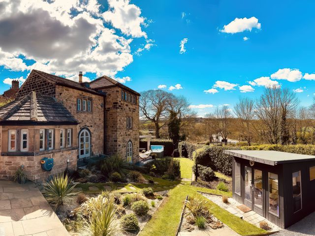 A stone house with garden plants and a small modern building at Dreamwood Cottage in Crigglestone near Newmillerdam